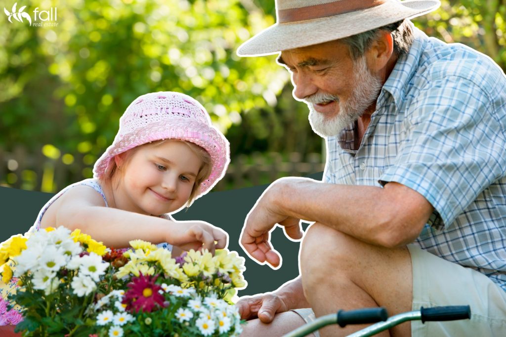 Image for blog: Low maintenance garden ideas for your home or investment. Image depicts a young girl and her grandfather doing some garden work on a batch of plants. Both are happy and smiling.